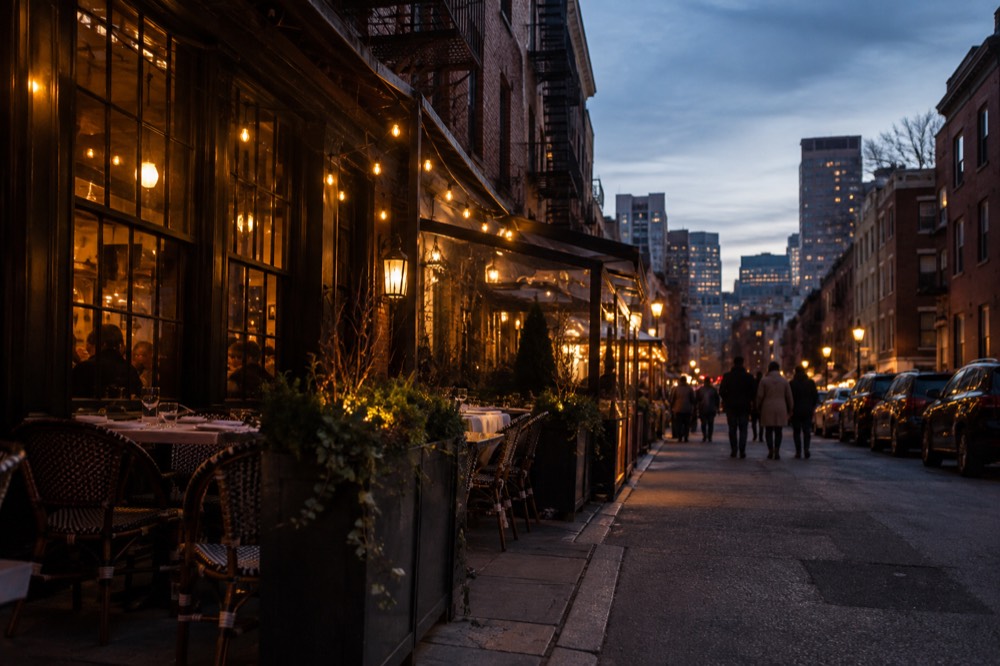 A busy Italian restaurant street in Boston's North End at dusk