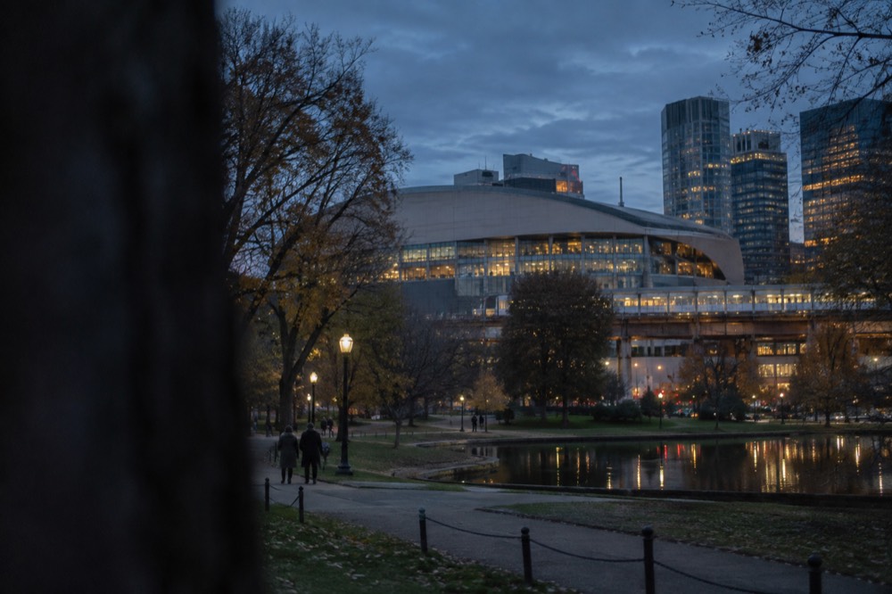 Exterior of a large sports arena above a rail station at dusk