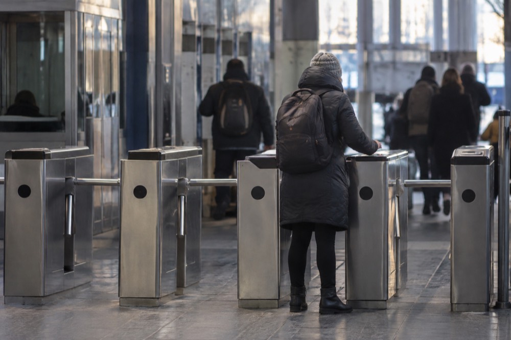 A rider inserting a paper ticket at a subway fare gate