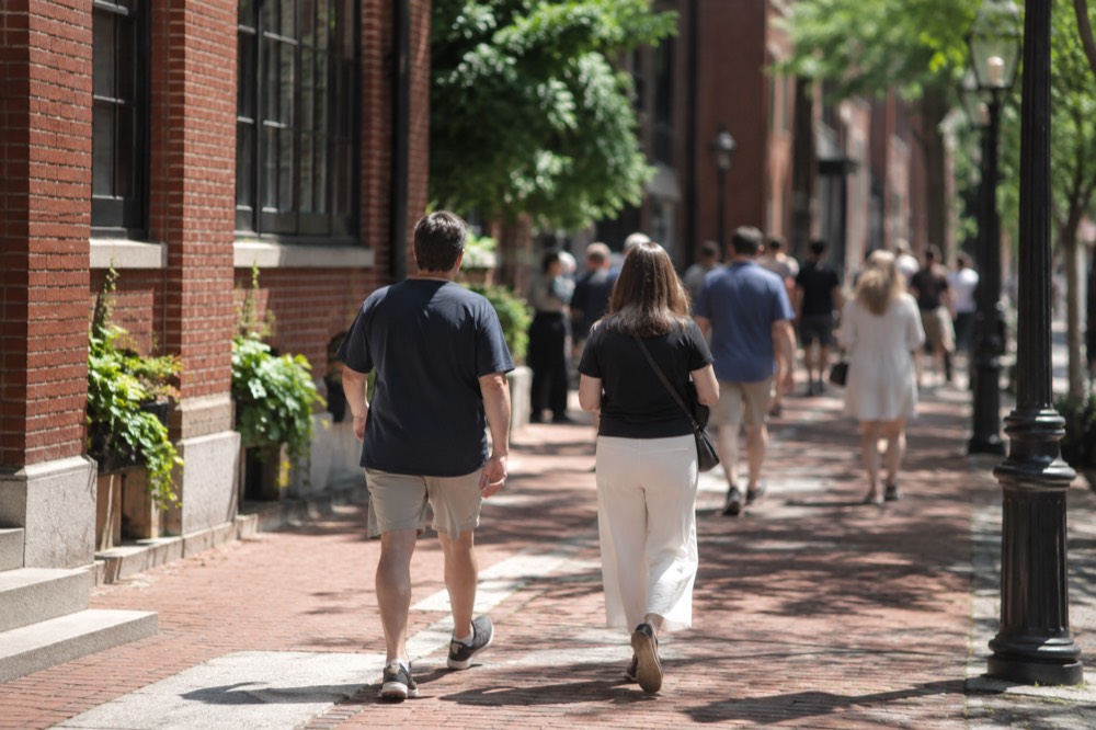 Visitors walking a red-brick historic street in downtown Boston on a sunny day