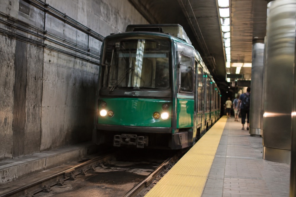 A green MBTA trolley arriving at an underground station platform in Boston