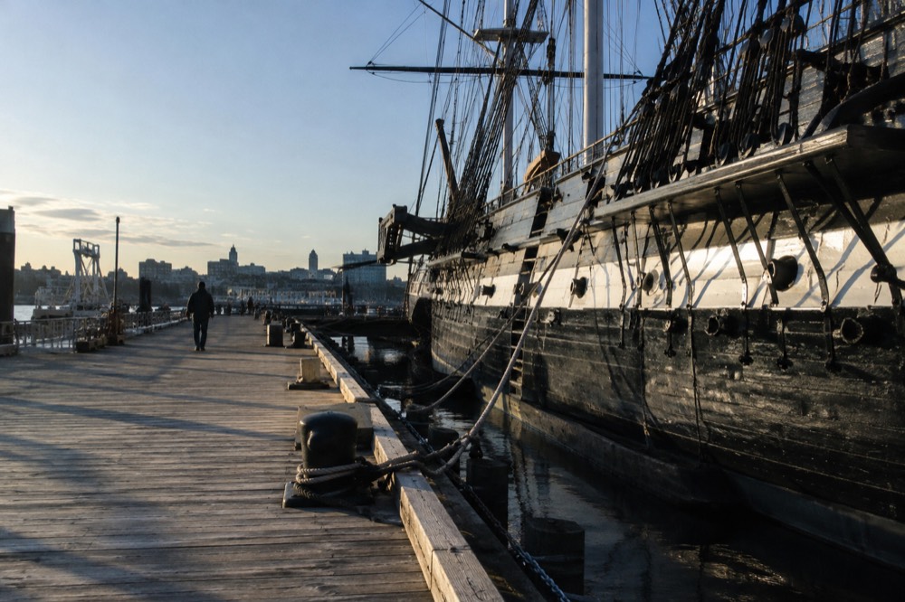 The wooden hull of the USS Constitution moored at the Charlestown Navy Yard pier