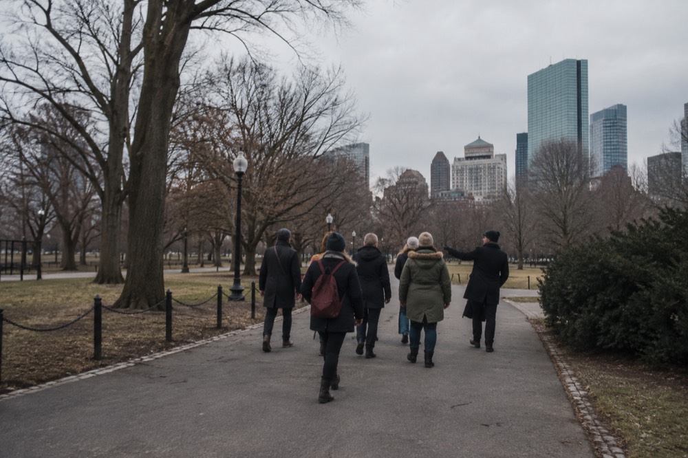 A guide leading a small group of visitors through a historic Boston street