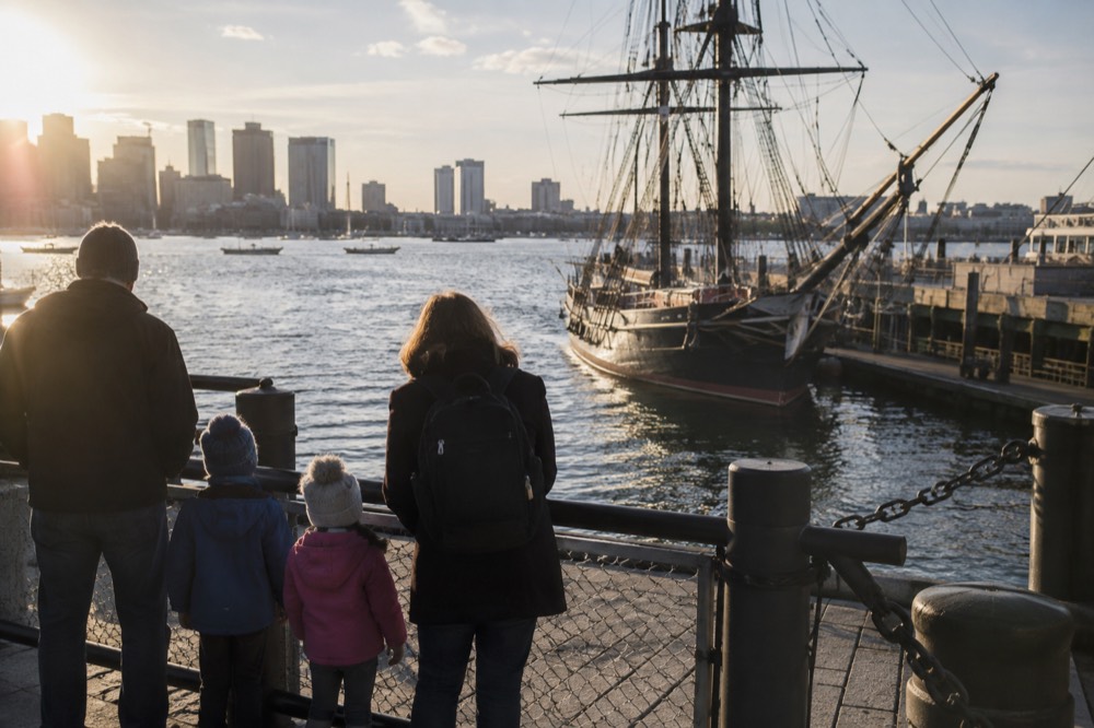 Family and children looking at a historic ship masts by the Boston waterfront