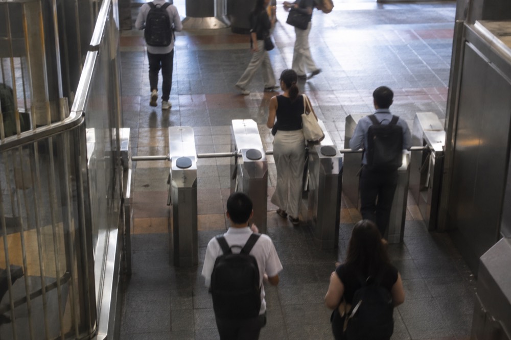 Commuters passing through a turnstile at a downtown Boston subway station