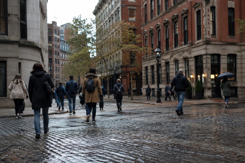 Pedestrians crossing a cobblestone street in downtown Boston