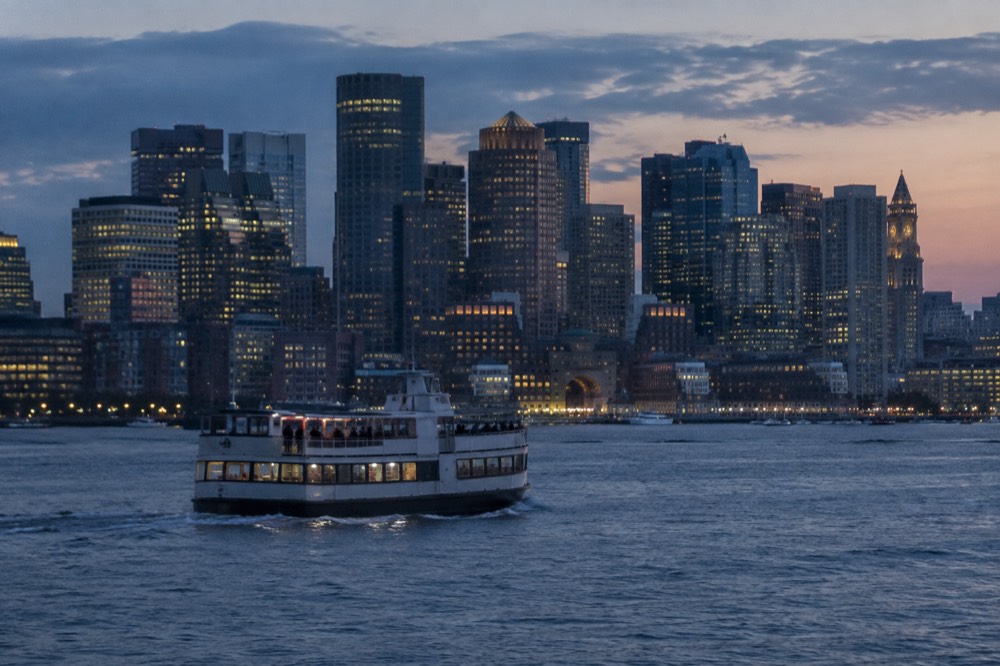 A ferry crossing Boston Harbor with the downtown skyline behind it