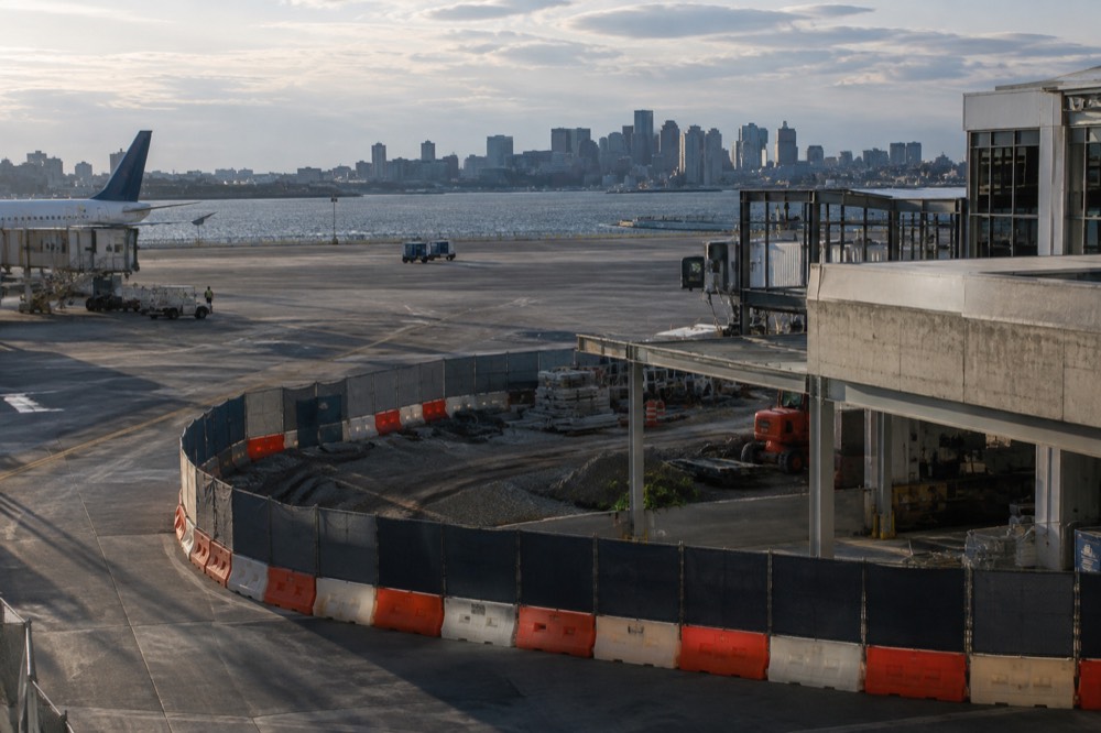 Airport terminal construction barriers and signage along a curved roadway