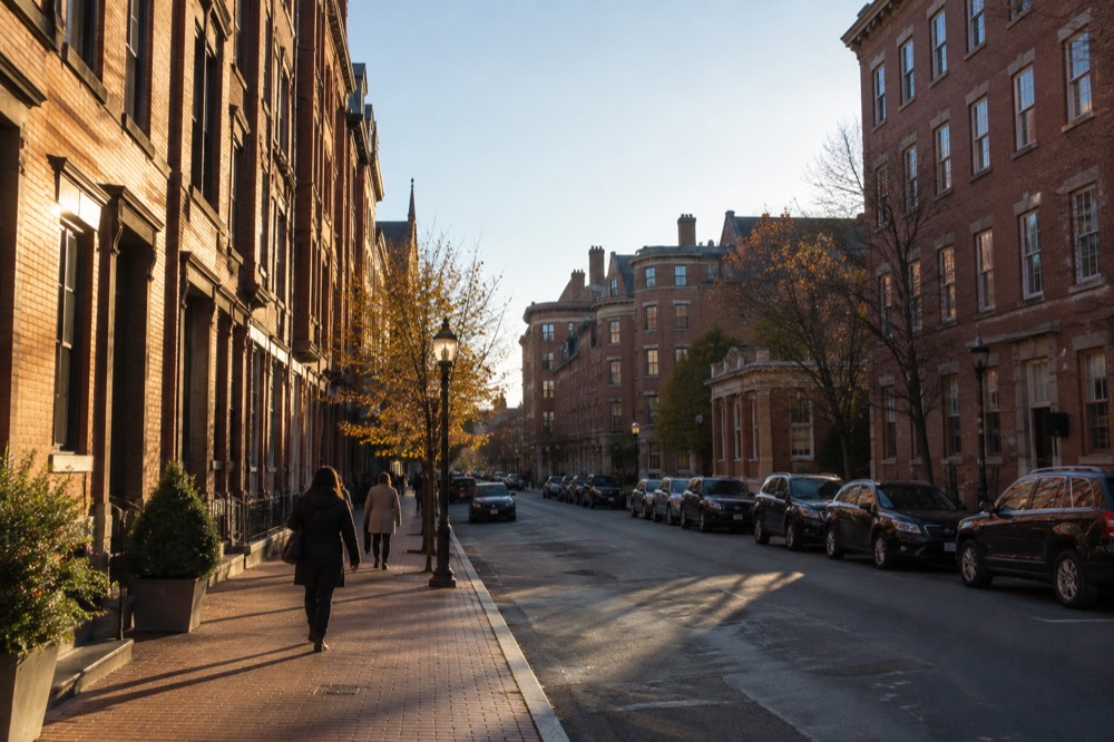 A downtown Boston street with brick buildings and pedestrians in late afternoon light