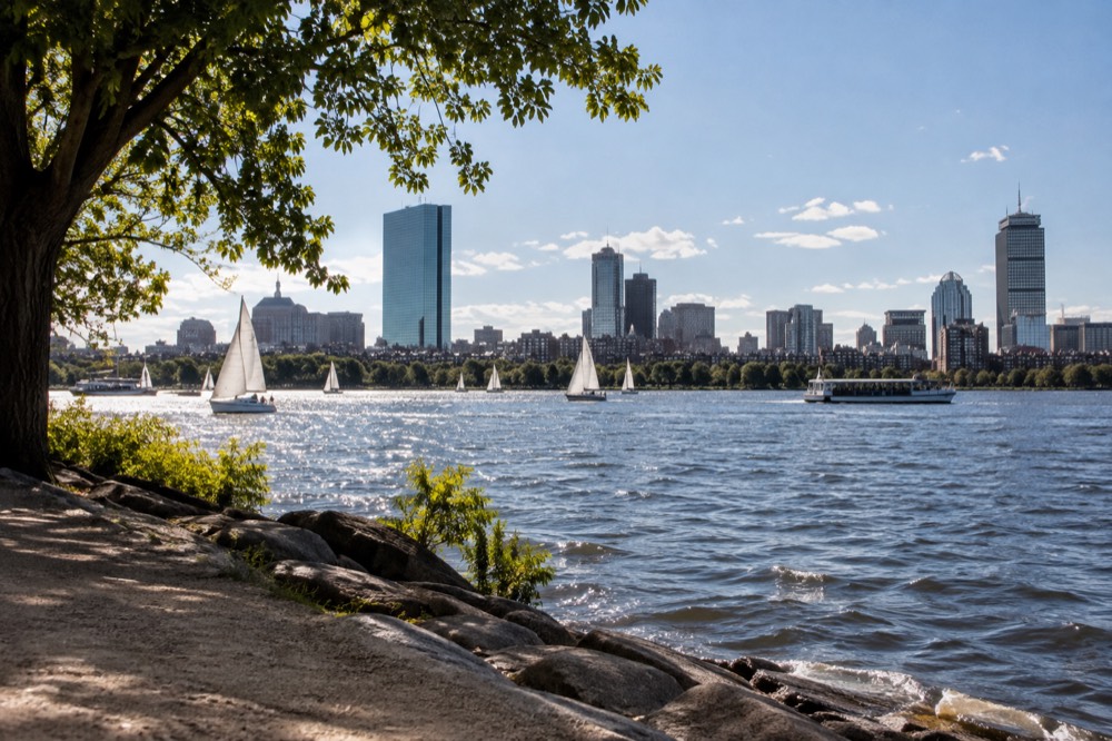Sailboats and a sightseeing boat on the Charles River with the Back Bay skyline behind them