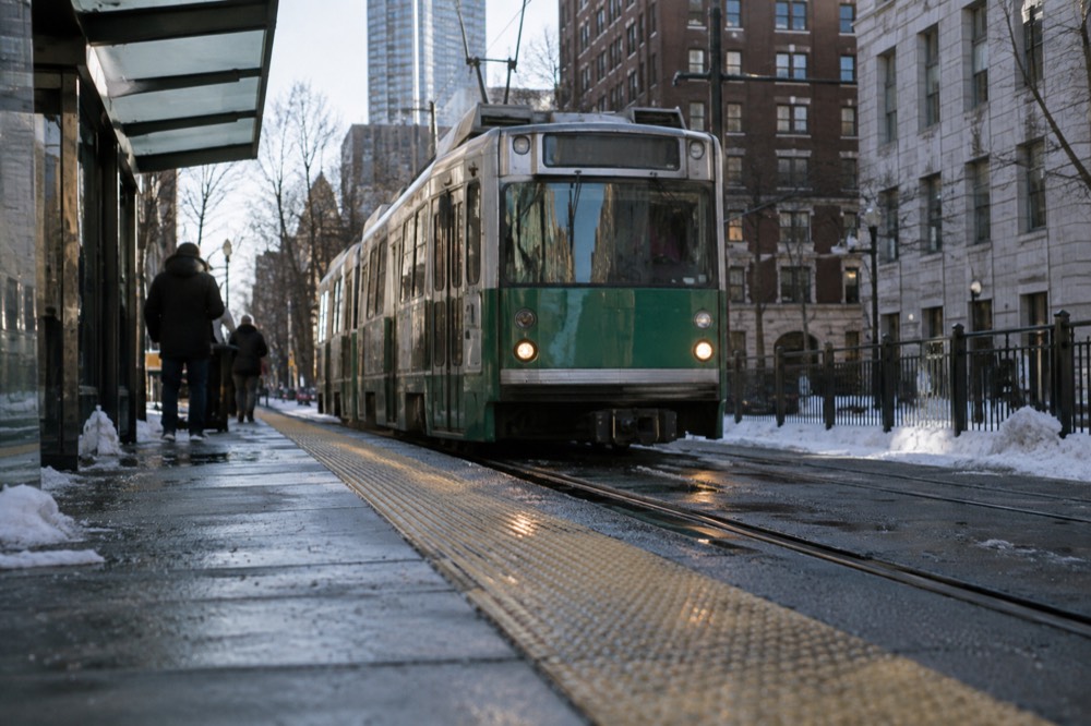 A Green Line trolley arriving at a street-level MBTA station in Boston