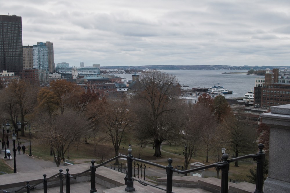 A view across Boston rooftops toward the harbor with ferries at a pier