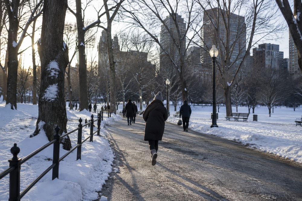 Snow-covered Boston sidewalks with pedestrians in winter coats walking carefully