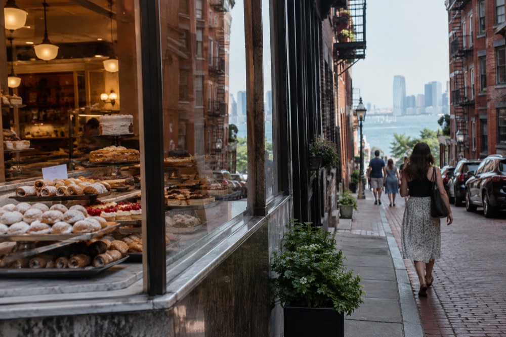 A pastry shop counter with trays of Italian cookies and cakes behind glass