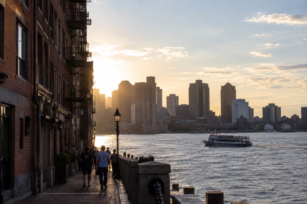 A sightseeing boat passing the Boston skyline on the harbor in late afternoon light