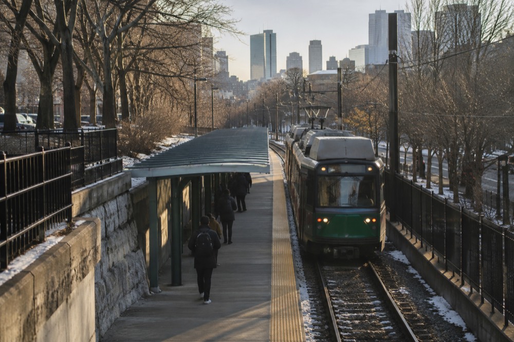 A Green Line subway train arriving at an outdoor MBTA station in Boston