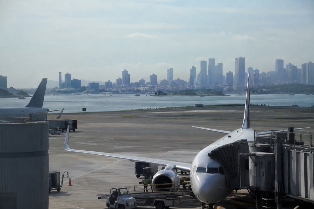Airplanes at Logan Airport with the Boston skyline visible across the harbor in the distance