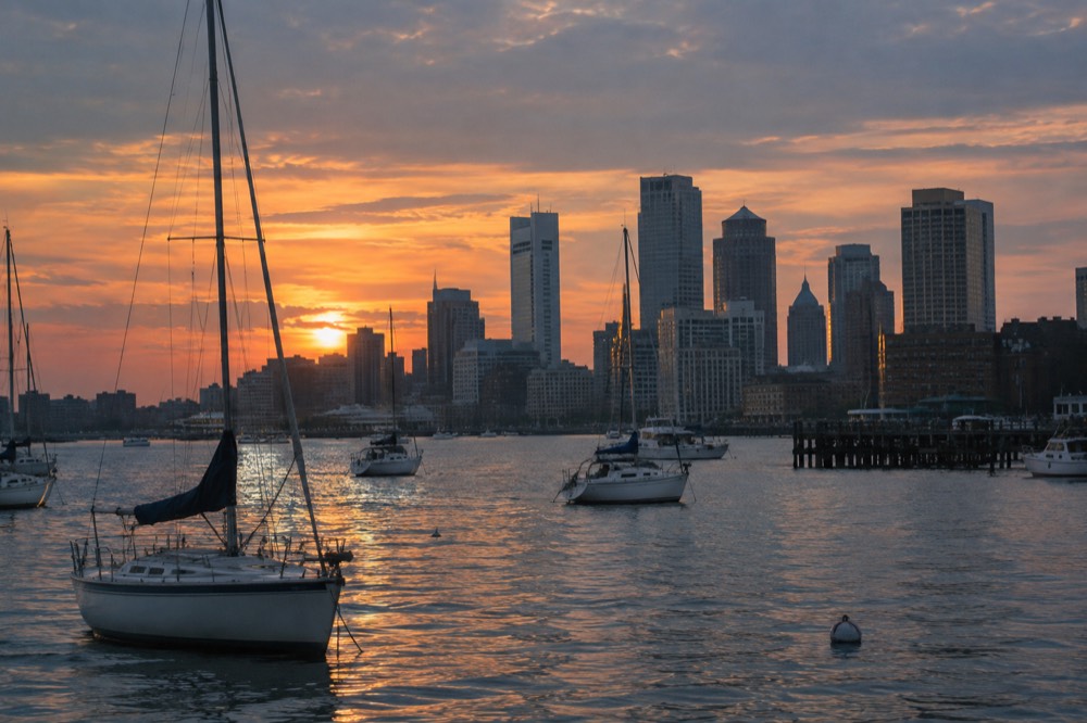 The Boston skyline at sunset seen from the harbor with boats in the foreground