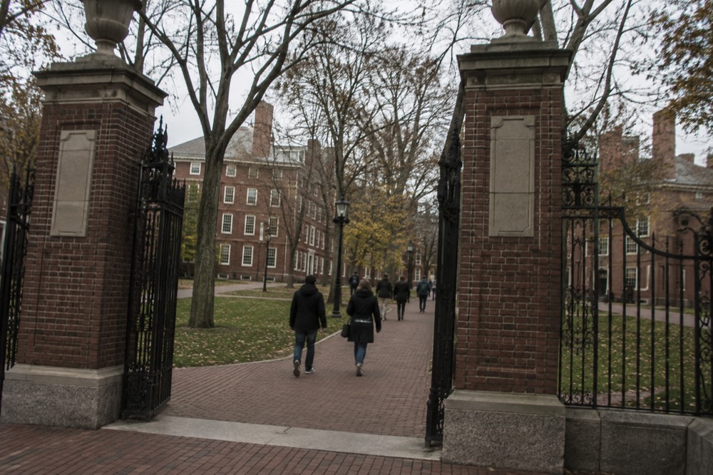 Visitors walking through the brick gates of Harvard Yard in Cambridge