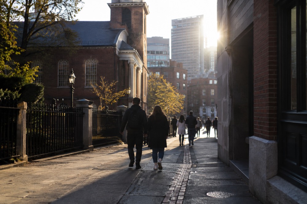 Visitors walking the red brick line of the Freedom Trail past an old church