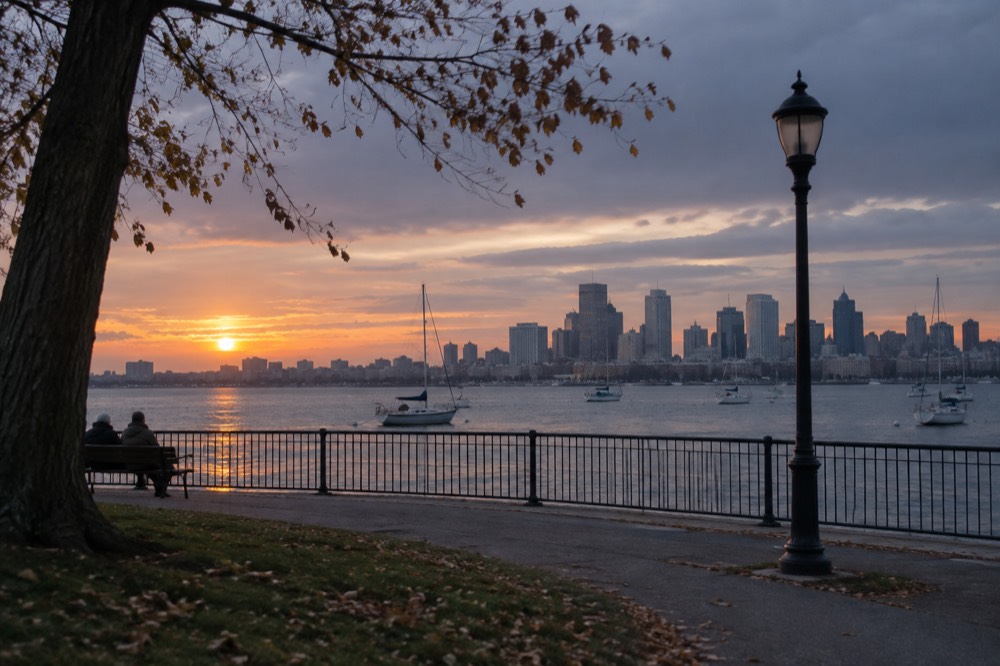 Boston skyline across the harbor at golden hour with boats in the foreground