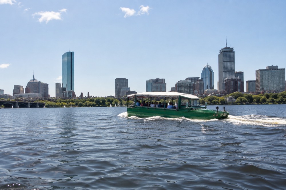 An amphibious duck boat cruising on the Charles River with the Boston skyline behind