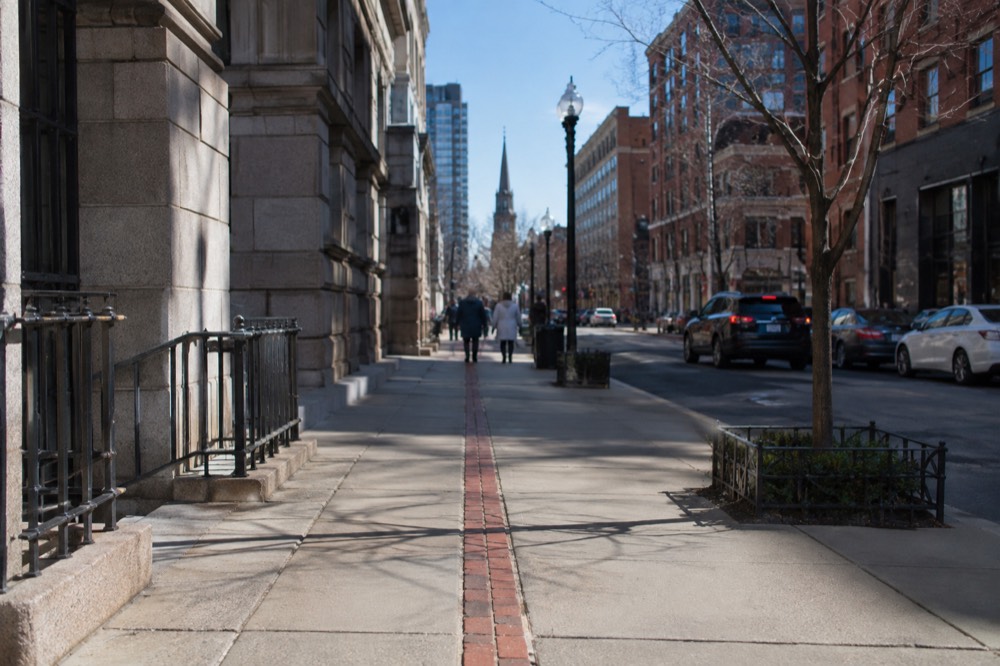 Red brick Freedom Trail line painted on a downtown Boston sidewalk