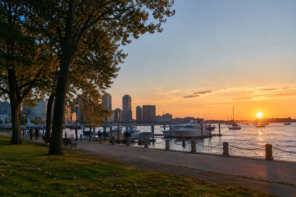 Boston harbor waterfront at sunset with boats moored along the pier