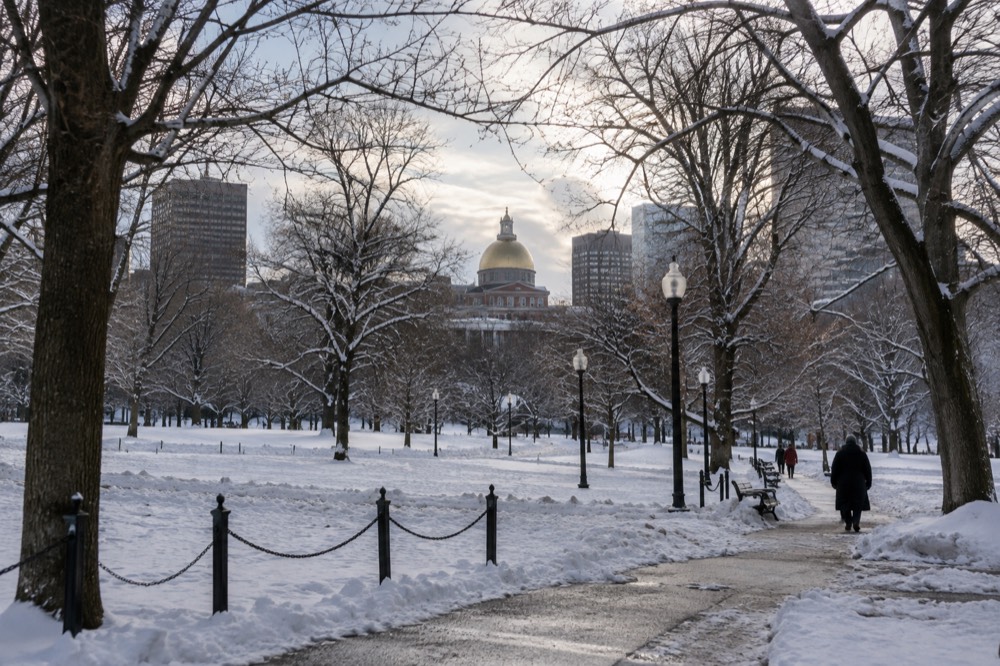 Snow-covered Boston Common with bare trees and the State House dome in the background