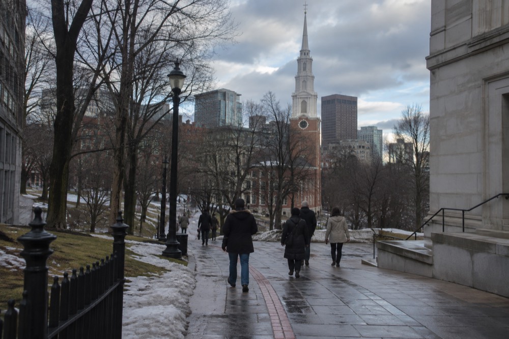 Visitors in winter coats walking the red brick line of the Freedom Trail past the Park Street Church