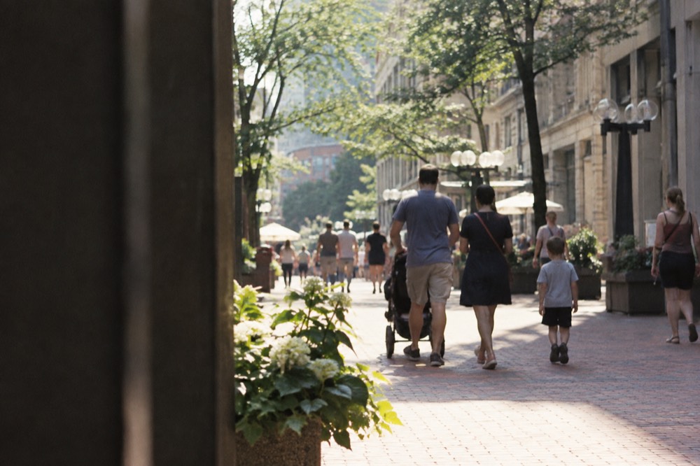Families walking a brick pedestrian mall in downtown Boston on a sunny afternoon