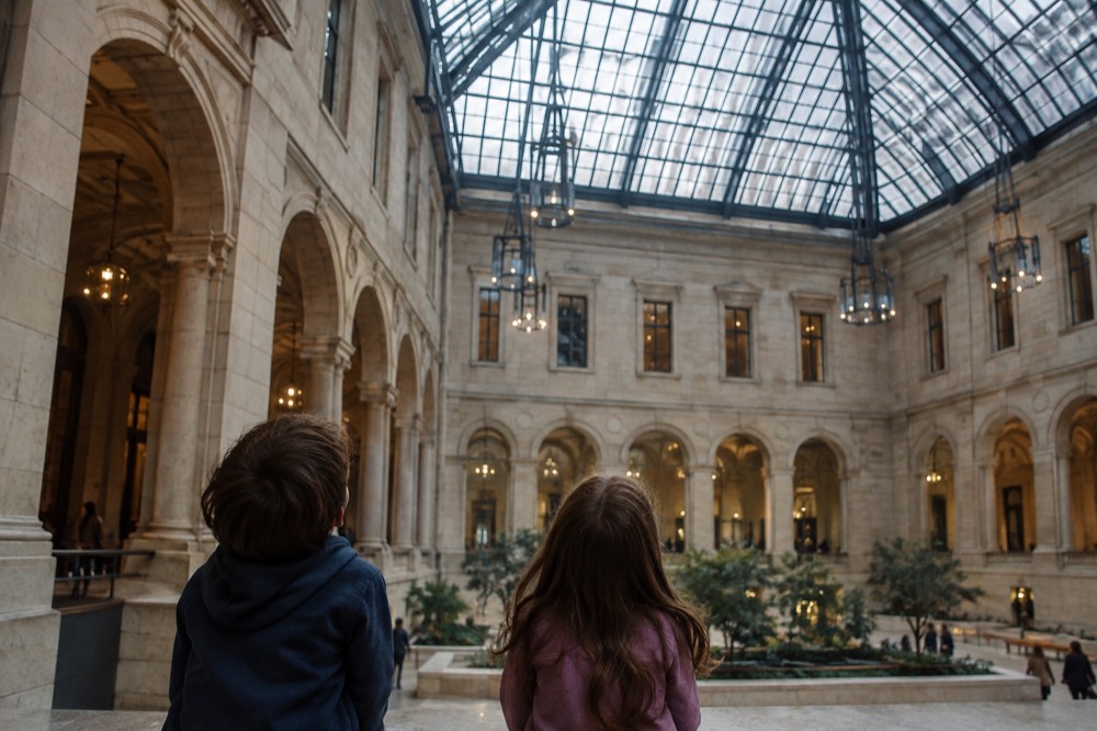 Children looking up at a tall glass atrium inside the Boston Public Library