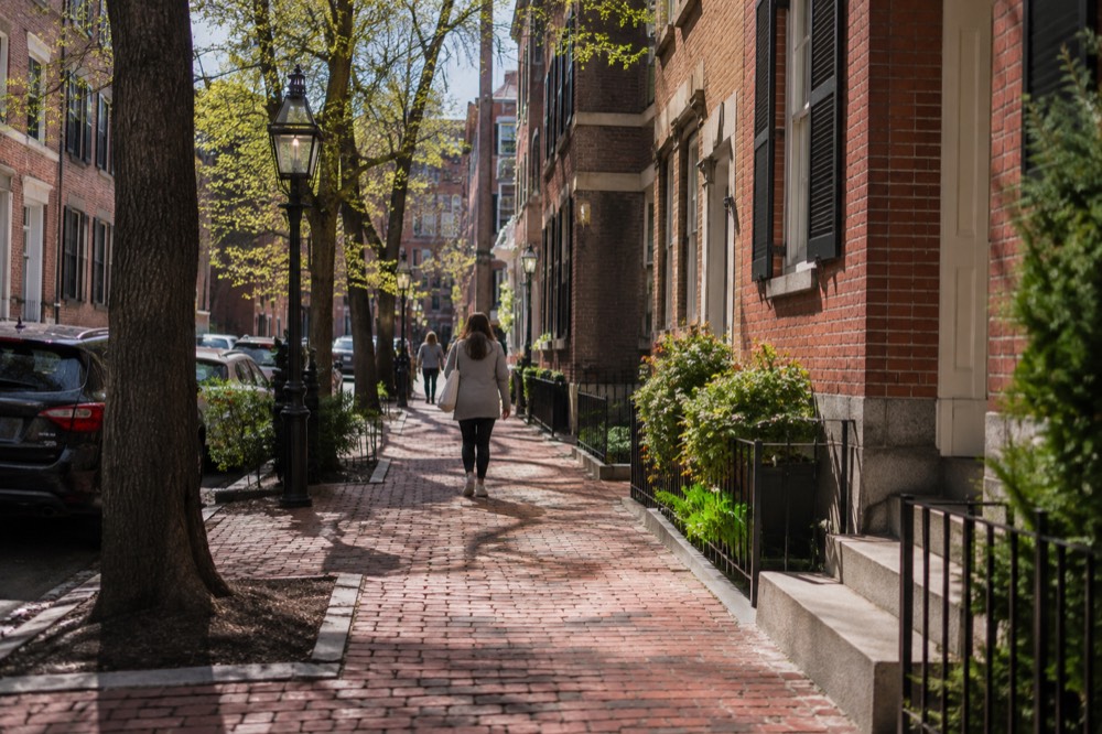 A red-brick sidewalk in downtown Boston with historic colonial-era buildings on both sides