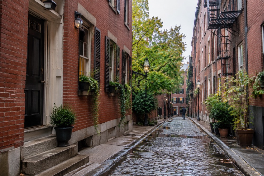 A red brick row house in the North End with a narrow alley and fire escape