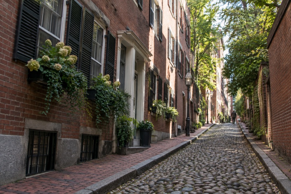 A quiet Beacon Hill alley of brick row houses with flower boxes and cobblestones
