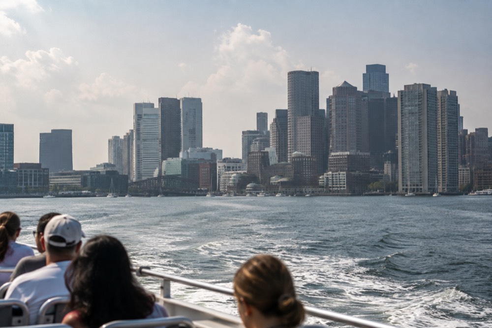 A sightseeing boat crossing Boston Harbor with the downtown skyline behind it
