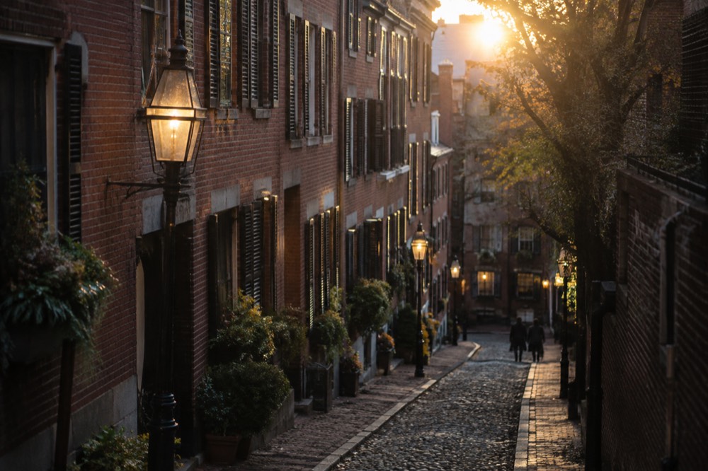 Gas lamps and brick row houses on a quiet Beacon Hill street at dusk