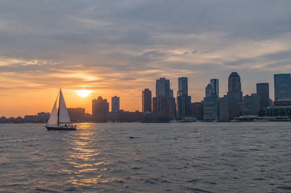 A sailboat passing the Boston skyline on a harbor cruise at sunset