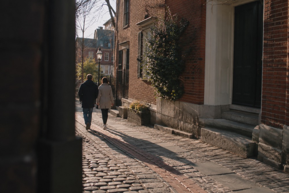 A couple strolling past historic brick buildings on the Freedom Trail in Boston